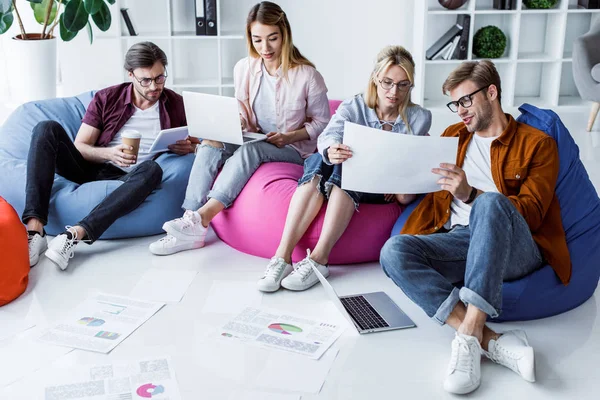 Colegas multiculturais trabalhando no projeto de inicialização no espaço de trabalho com laptops e documentos — Fotografia de Stock