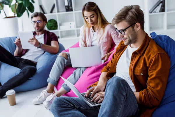 Multicultural colleagues working on startup project in office and sitting on bean bag chairs — Stock Photo