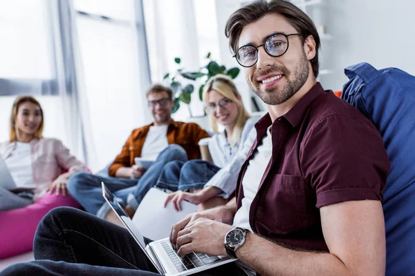Multicultural colleagues working on startup project in office with laptop and looking at camera — Stock Photo