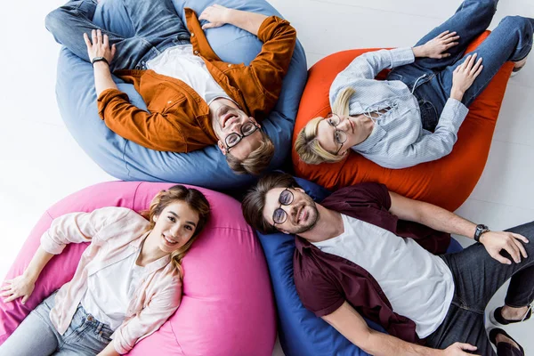 Multikulturelle Kollegen des Startup-Projekts liegen auf Sitzsäcken im Büro — Stockfoto