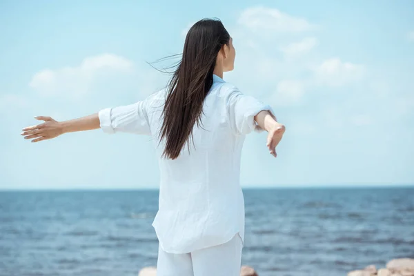 Visão traseira da mulher de pé com os braços estendidos pelo mar — Fotografia de Stock
