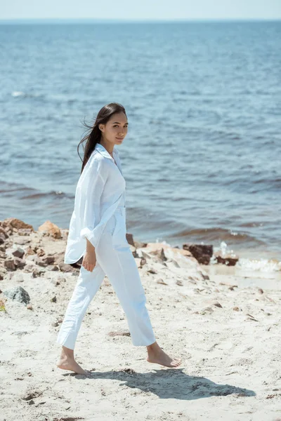 Attractive young asian woman walking on beach by sea — Stock Photo