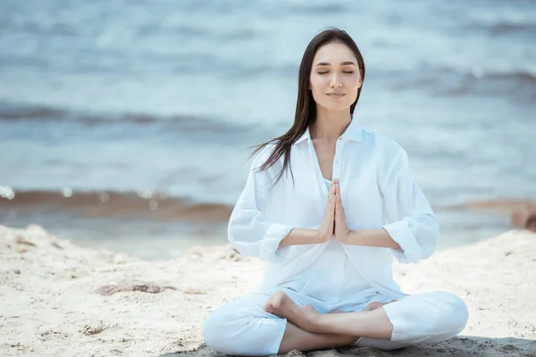 Attractive young asian woman in anjali mudra (salutation seal) pose on beach — Stock Photo