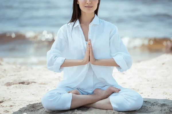 Cropped image of woman in anjali mudra (salutation seal) pose on beach by sea — Stock Photo