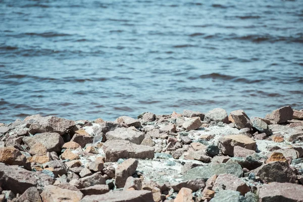 Selective focus of rocky beach and wavy sea behind during daytime — Stock Photo