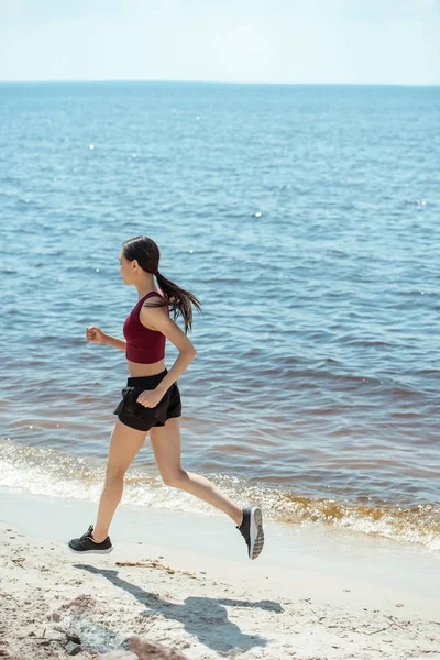 Vue latérale de la jeune sportive asiatique courir sur la plage — Photo de stock