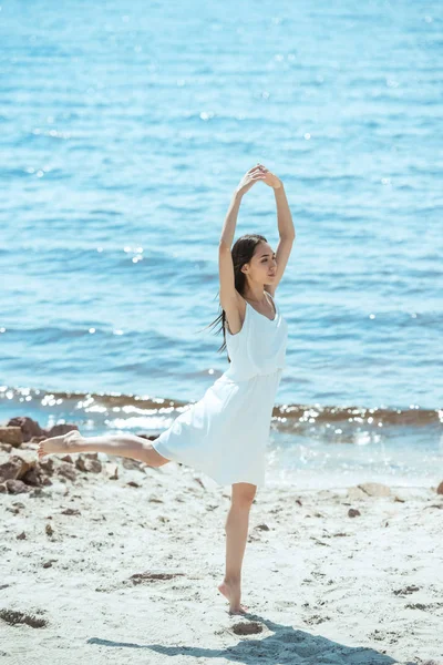 Jovem mulher asiática em vestido branco dançando na praia por mar — Fotografia de Stock