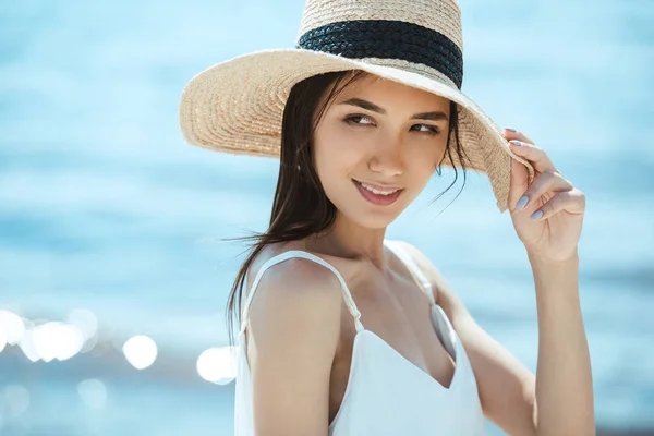 Foco seletivo de mulher asiática atraente em chapéu de palha olhando para longe — Fotografia de Stock