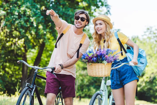 Portrait of young couple with backpacks and bicycles in park — Stock Photo