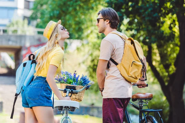 Visão traseira do jovem casal com mochilas e bicicletas no parque — Fotografia de Stock
