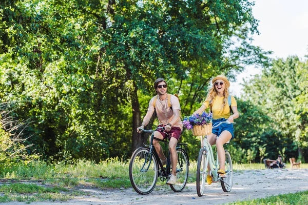 Joven feliz pareja montar bicicletas retro en el parque en el día de verano - foto de stock