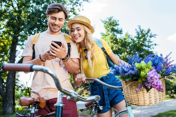 Sonriente pareja usando smartphone en el parque en el día de verano - foto de stock