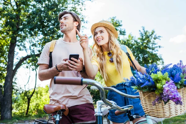 Young couple with smartphone in park on summer day — Stock Photo