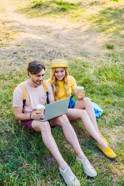 Jovem casal com café para ir usando laptop no parque — Fotografia de Stock