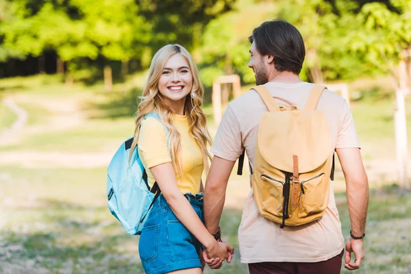 Coppia felice innamorata che si tiene per mano mentre cammina nel parco estivo insieme — Foto stock