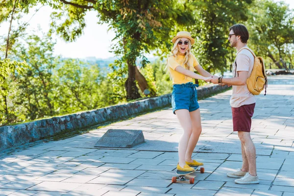 Homme aider copine patinage sur longboard sur rue — Photo de stock