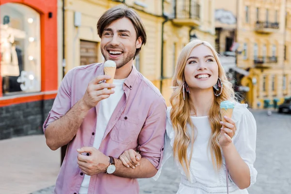 Porträt eines jungen Paares mit Eis, das an einem Sommertag auf der Straße spaziert — Stockfoto