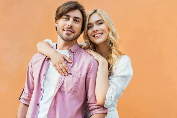 Portrait of young stylish couple looking at camera while standing against city building wall — Stock Photo