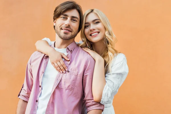 Retrato de pareja joven y elegante mirando a la cámara mientras está de pie contra la pared del edificio de la ciudad — Stock Photo