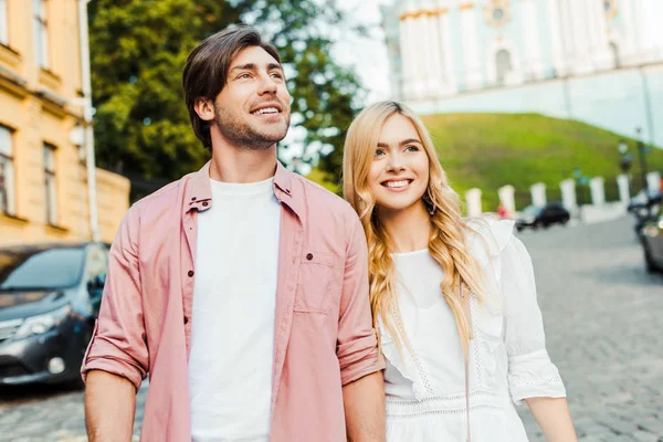 Retrato de pareja sonriente mirando hacia la calle de la ciudad - foto de stock