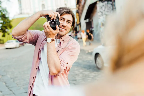 Vista parcial del hombre sonriente tomando la foto de la novia en la cámara fotográfica en la calle - foto de stock