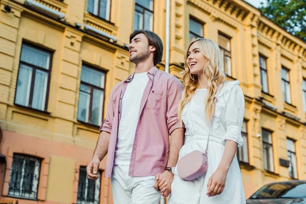 Young couple holding hands while walking on city street together — Stock Photo