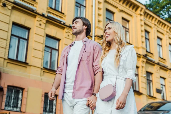 Pareja joven tomados de la mano mientras caminan juntos por la calle de la ciudad - foto de stock