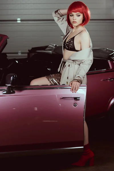 Beautiful stylish girl opening vintage car and looking away — Stock Photo