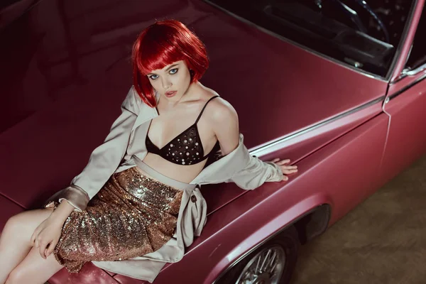 High angle view of beautiful stylish girl sitting on vintage car and looking at camera — Stock Photo