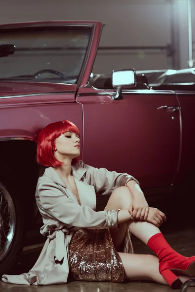 Hermosa mujer joven en gabardina de moda sentado cerca de coche retro - foto de stock