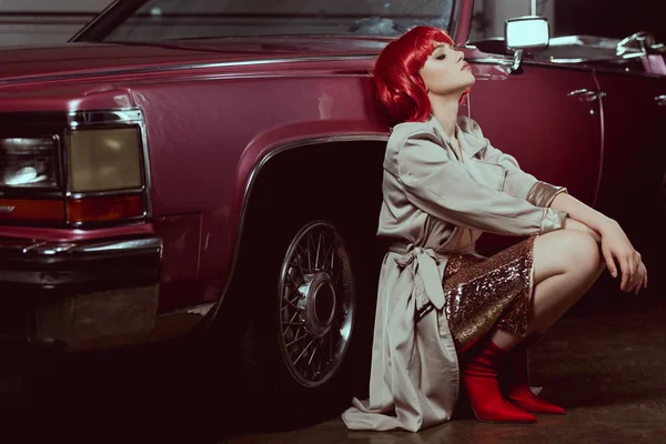 Beautiful stylish young woman with closed eyes crouching near vintage car — Stock Photo