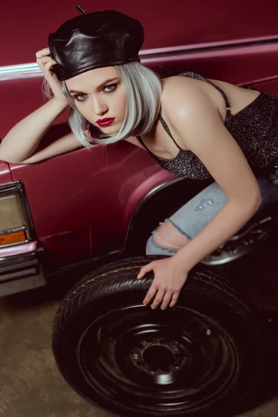 Високий кут зору чуттєвої молодої жінки, що змінює колесо автомобіля і дивиться на камеру — стокове фото