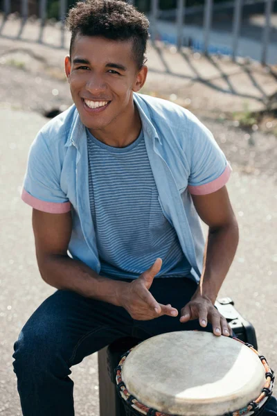 African american guy playing djembe in urban environment — Stock Photo