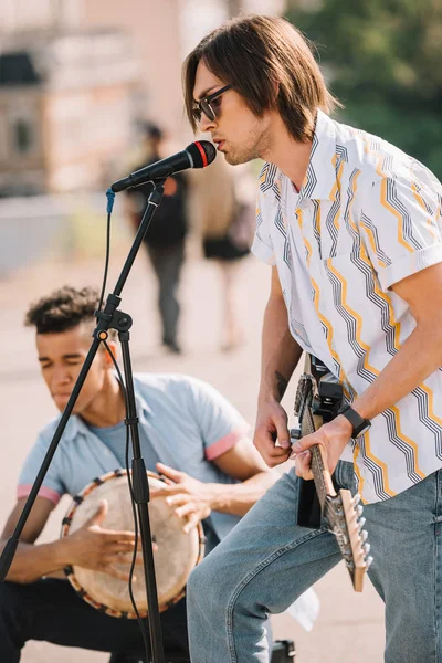 Jóvenes buskers felices baterista y guitarrista tocando música en la calle de la ciudad - foto de stock