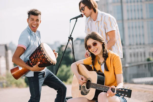 Jóvenes multirraciales que interpretan diferentes instrumentos musicales en la calle - foto de stock