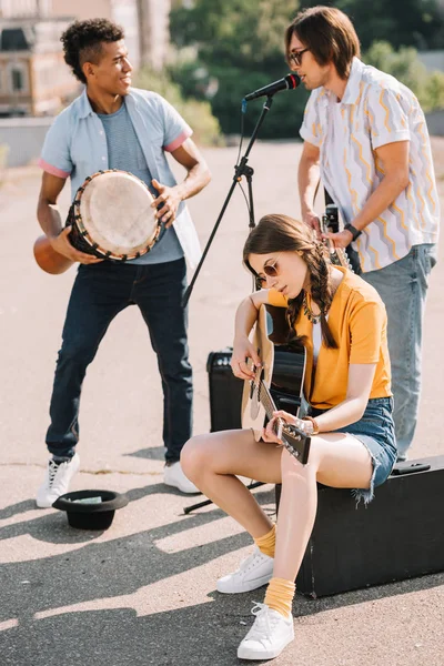 Jóvenes y felices músicos callejeros multirraciales en la ciudad - foto de stock