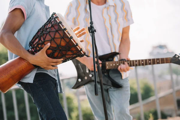 Cropped view of multiracial men performing on sunny city street — Stock Photo