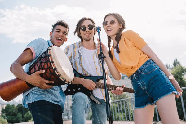 Young happy buskers singing by microphone at city street — Stock Photo