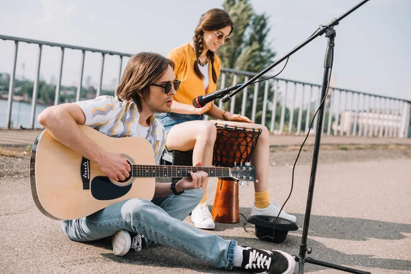 Jóvenes y felices músicos callejeros tocando en la ciudad - foto de stock