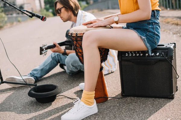 Woman with djembe and man with guitar performing on sunny city street — Stock Photo