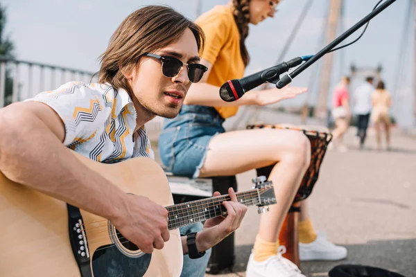 Joven y feliz guitarrista masculino y cantante femenina en la ciudad - foto de stock