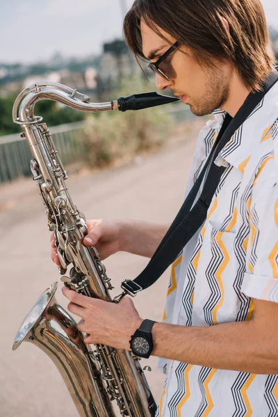 Jovem com saxofone tocando na ensolarada rua da cidade — Fotografia de Stock