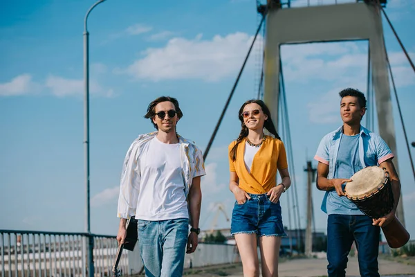 Equipe de jovens amigos carregando instrumentos musicais em ambiente urbano — Fotografia de Stock