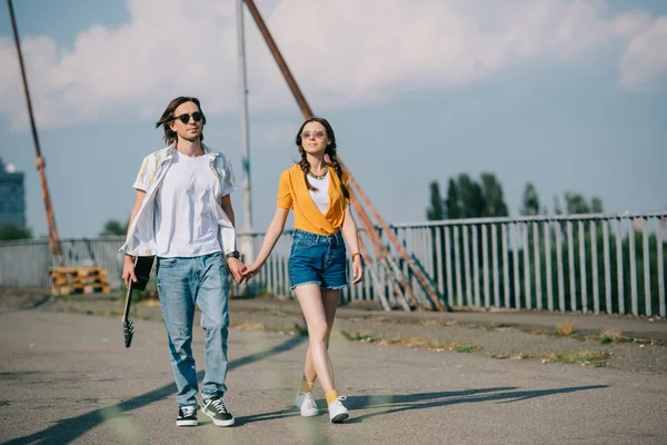 Jeune fille marchant et tenant la main du gars avec guitare sur la rue — Photo de stock