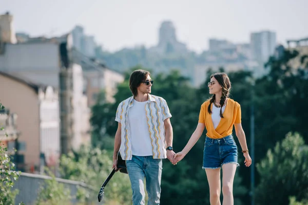 Пара молодых друзей гуляют и держатся за руки в городской среде — стоковое фото