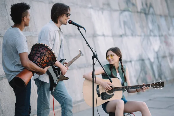 Young happy buskers playing music and singing at city street — Stock Photo