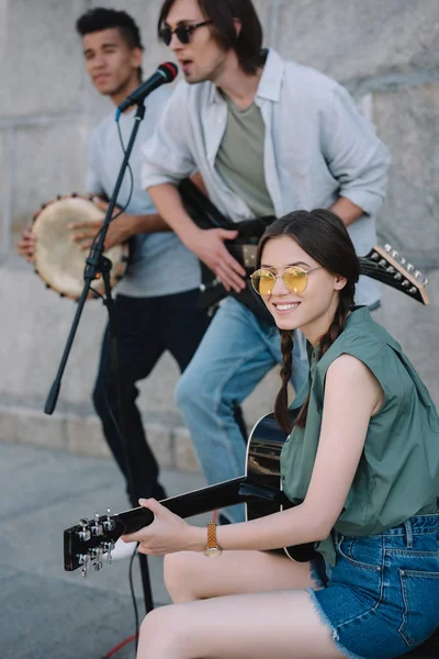 Jovens multirraciais com guitarras e djembe tocando na rua — Fotografia de Stock