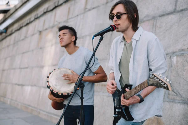 Équipe de jeunes amis multiraciaux masculins jouant de la musique et chantant en milieu urbain — Photo de stock