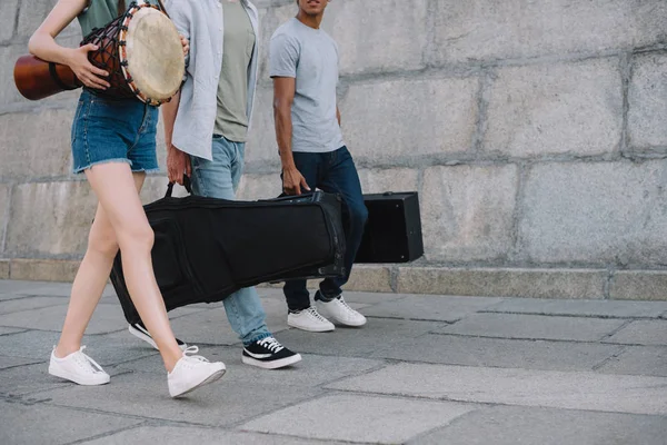 Обрезанный вид молодых людей в группе, ходящих и несущих музыкальные инструменты — стоковое фото