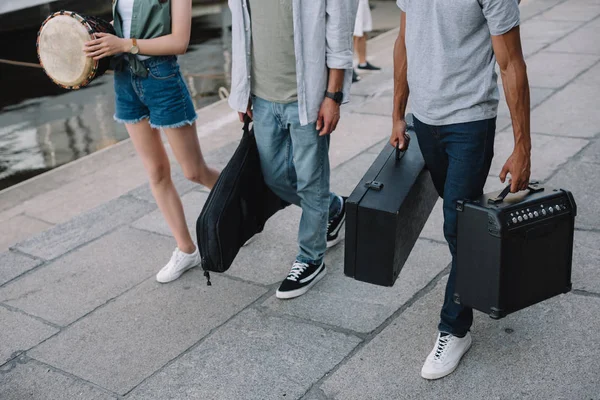 Cropped view of street musicians walking and carrying musical instruments — Stock Photo